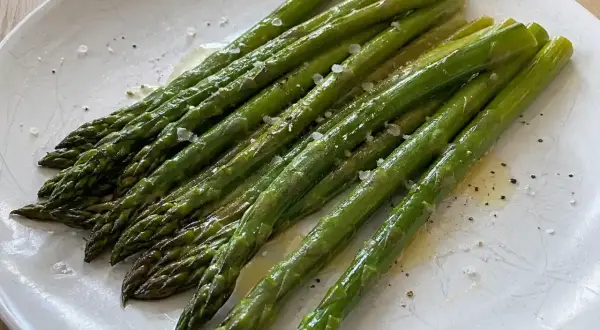 När man ska koka sparris är det viktigt att den blir perfekt. Här ligger en vackert grön, nykokt sparris på ett fat, strödd med flingsalt och peppar.