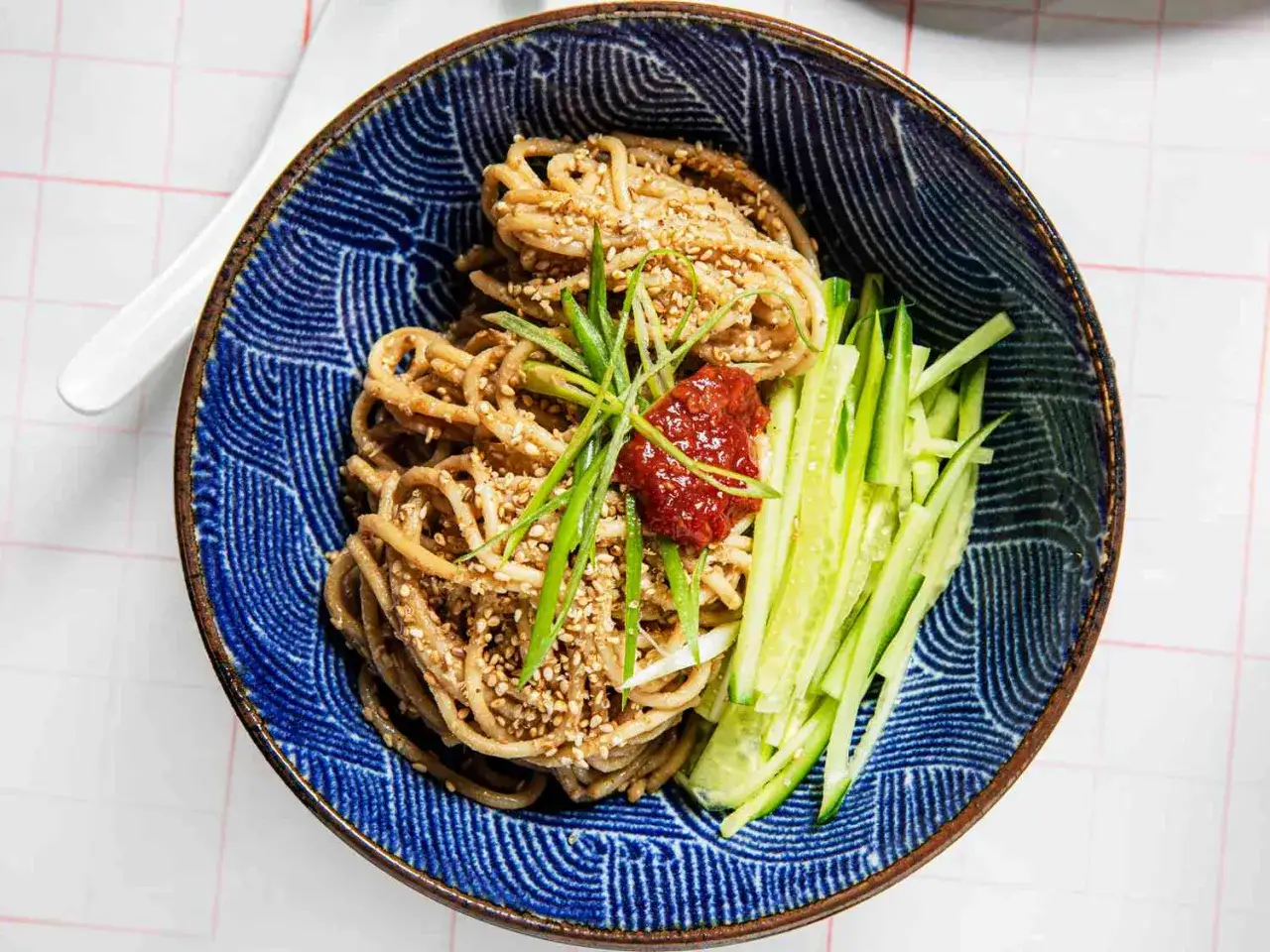 En sk&aring;l med asiatisk nudelsallad med gurka, sesamfr&ouml;n och en klick chilis&aring;s.
