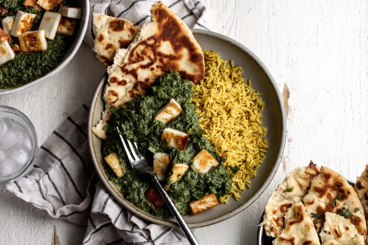 En skål med krämig palak paneer, gyllene ris och naanbröd. Ett perfekt palak paneer recept för en smakrik måltid.