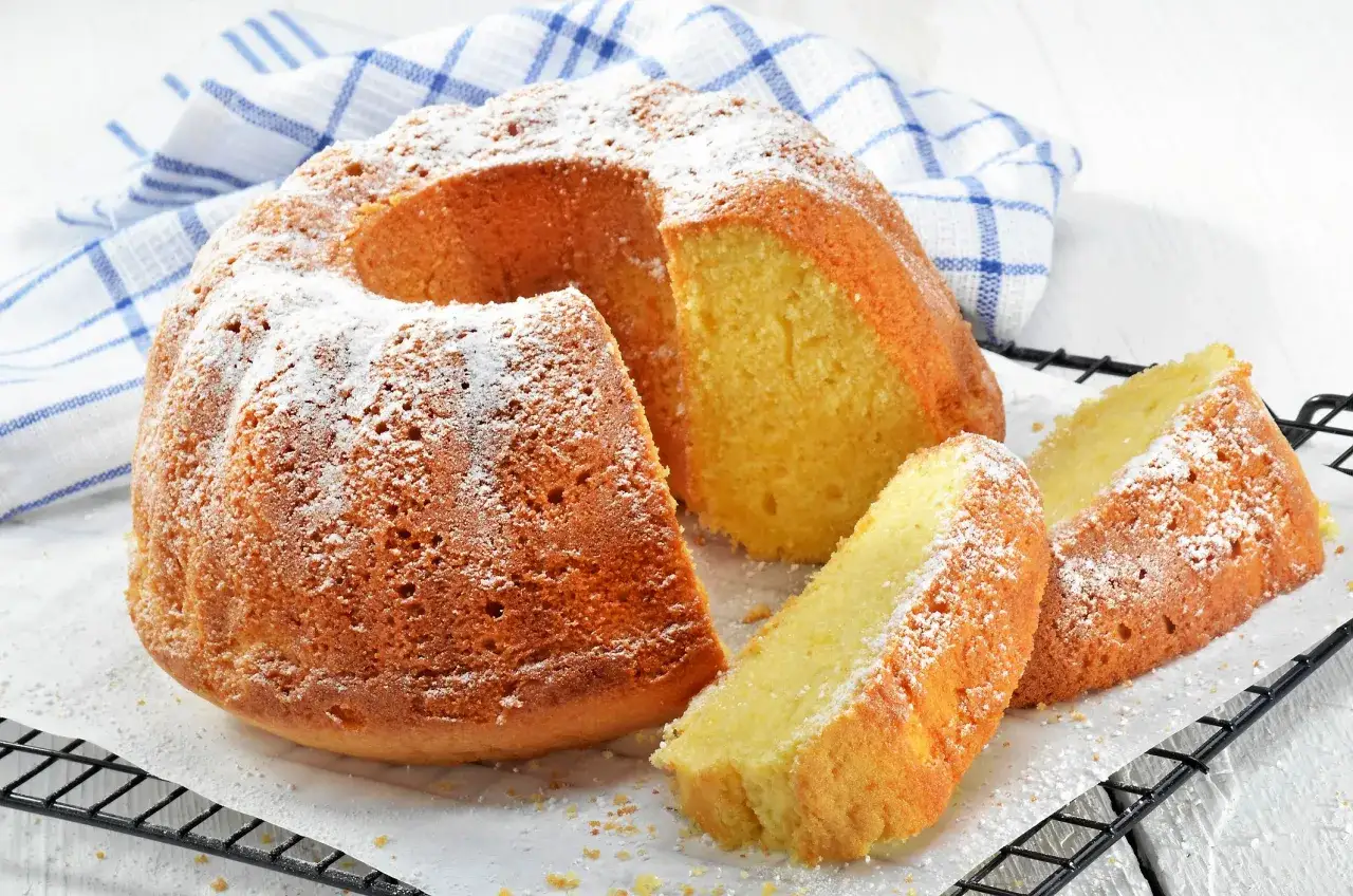 En gyllene sockerkaka, pudrad med florsocker, med tv&aring; skivor upplagda. Perfekt f&ouml;r fika med mjuka kakor.