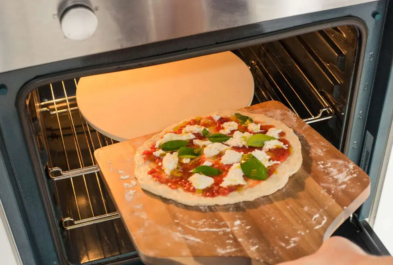 En hemlagad pizza med tomats&aring;s, mozzarella och basilika &auml;r redo att bakas i ugnen. Ett perfekt pizza recept f&ouml;r hemmakockar.