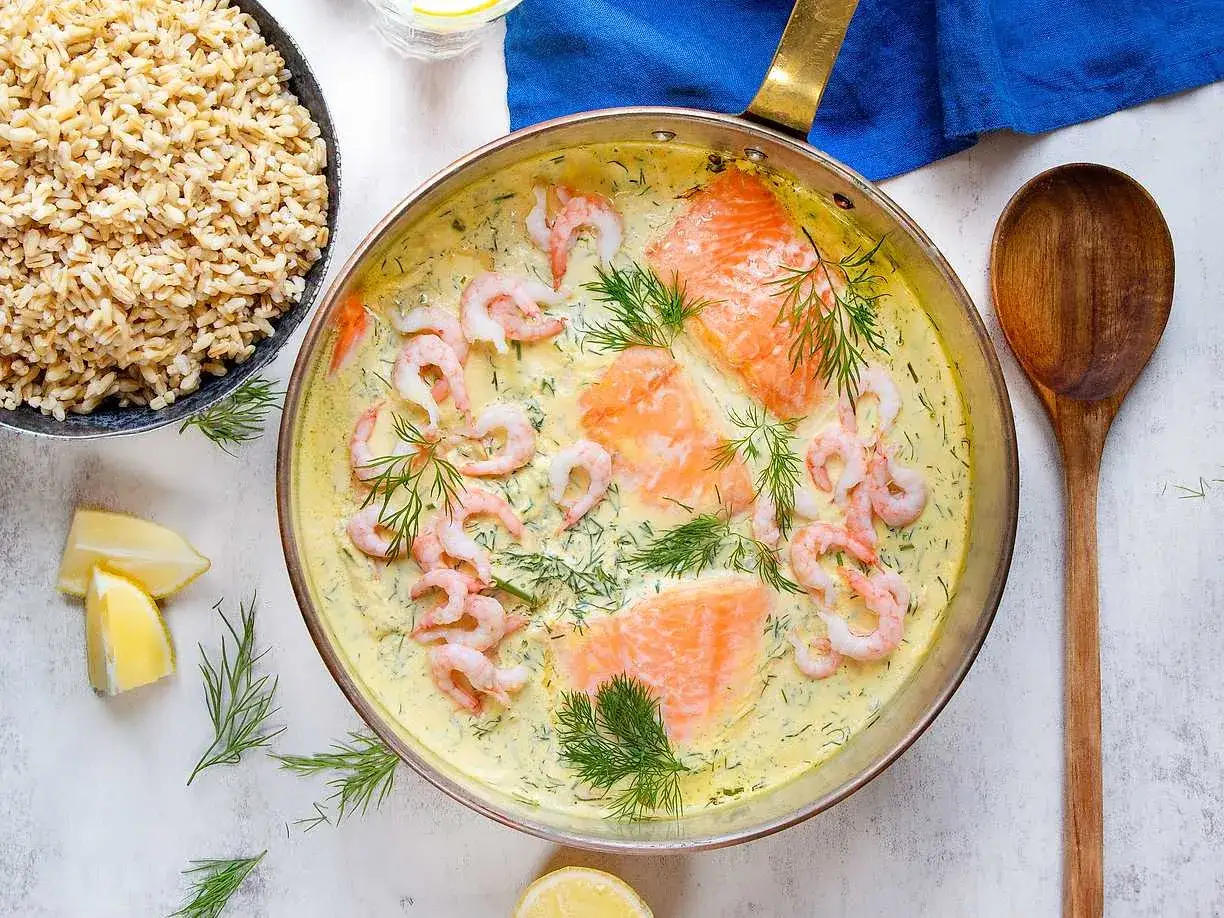 Laxfil&eacute;er och r&auml;kor i en kr&auml;mig s&aring;s till lax, garnerad med dill och citronklyftor. Serveras med fullkornsris.