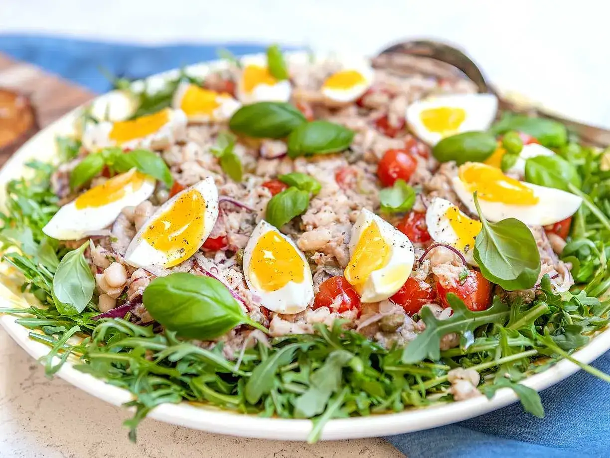 En h&auml;rlig tonfisk sallad med &auml;gg, tomater, b&ouml;nor och basilika, serverad p&aring; en b&auml;dd av ruccola.