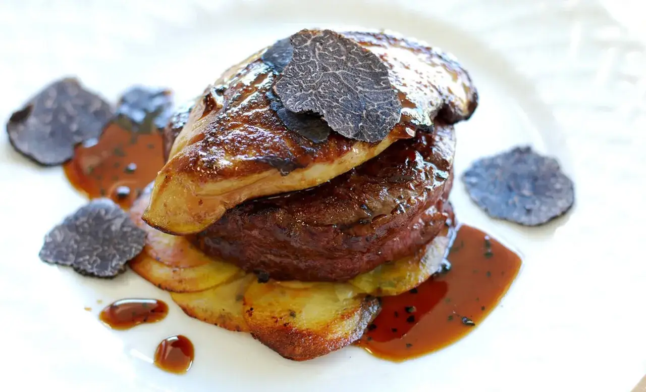 En lyxig tournedos Rossini med anklever, tryffel och potatis, serverad med en mustig sås.