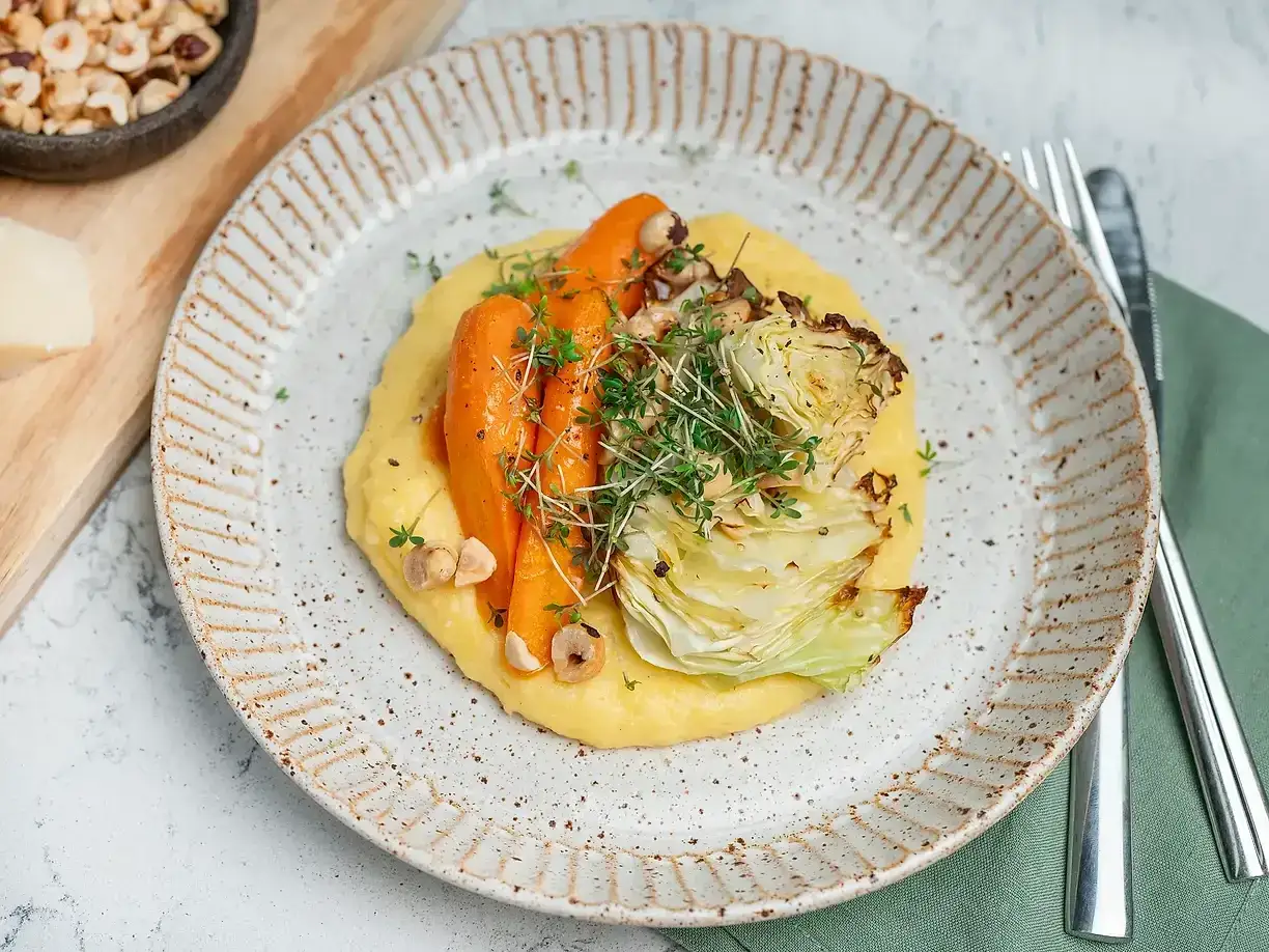 En krämig polenta med rostade rotfrukter och krispiga hasselnötter. Ett härligt polenta recept för en smakrik måltid.