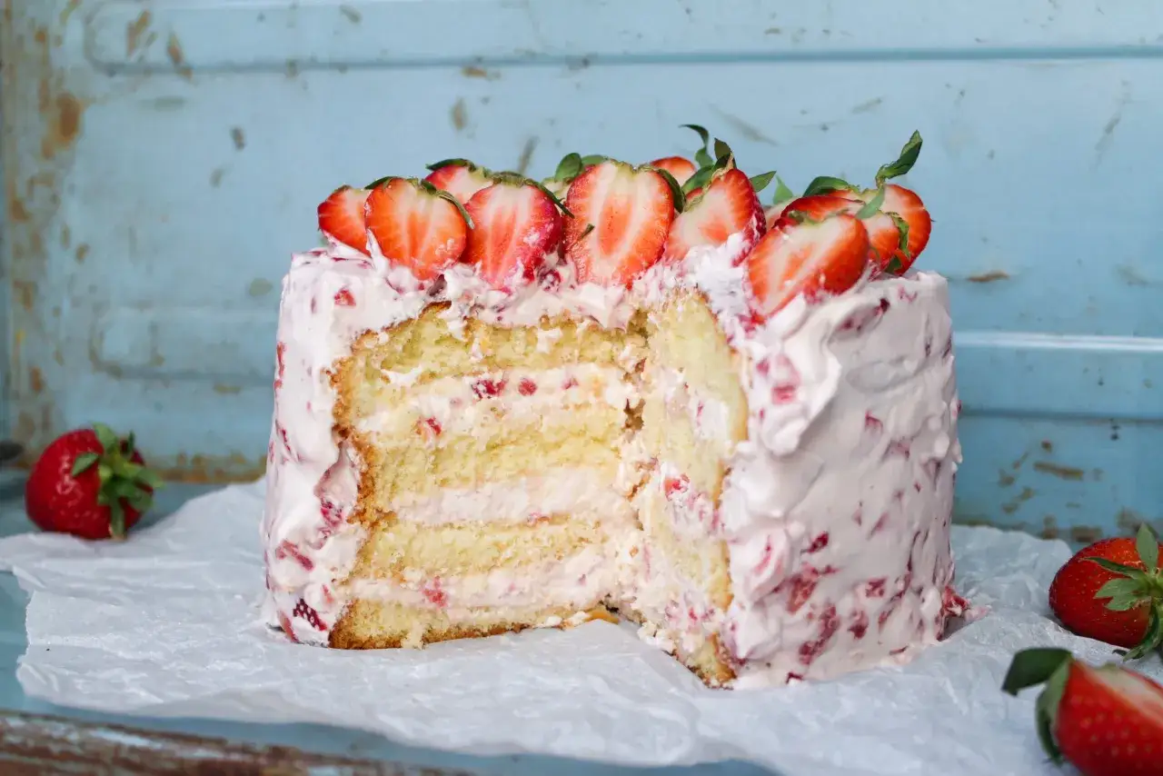 En saftig tårta i långpanna med jordgubbsfrosting och färska jordgubbar.