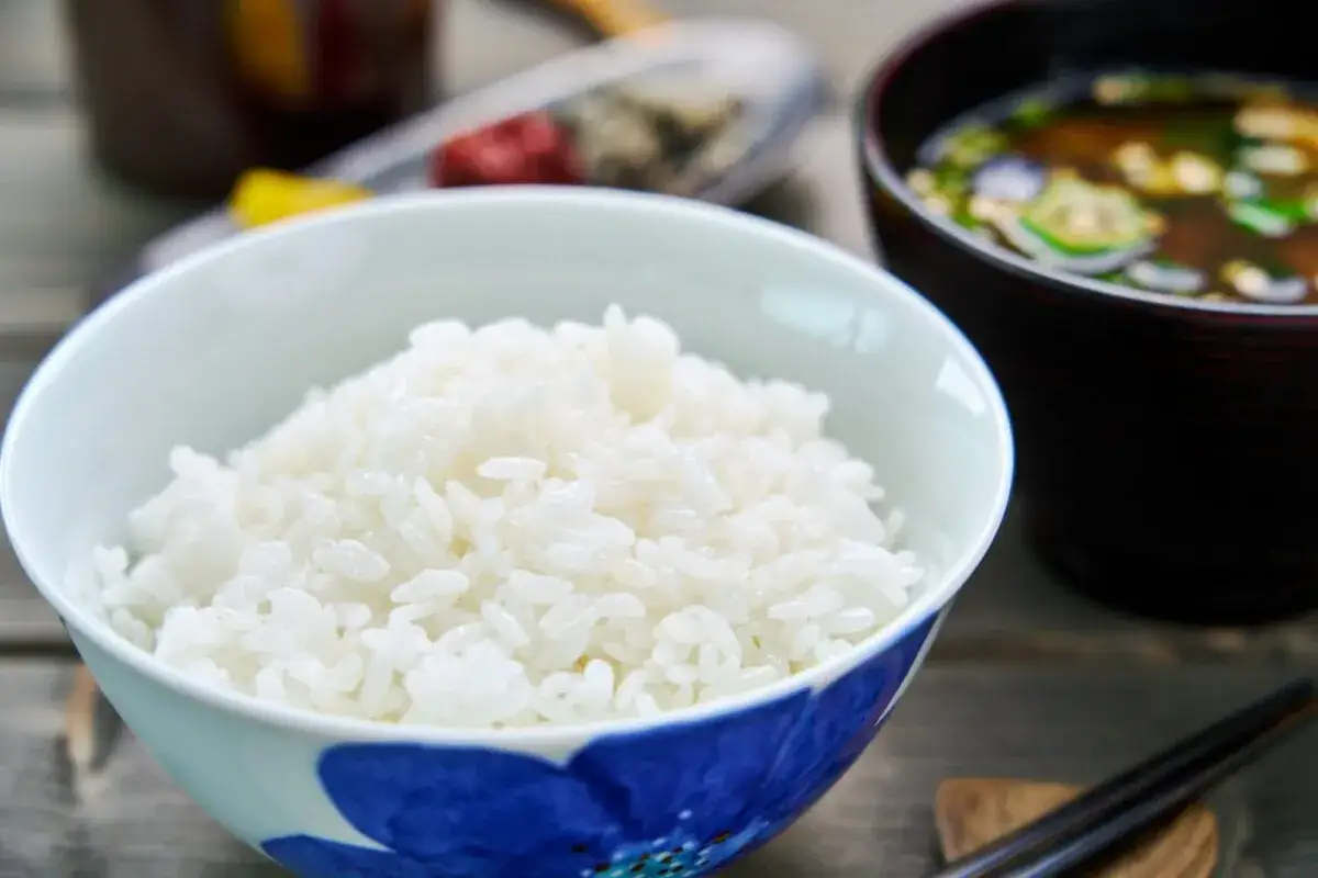 En sk&aring;l med fluffigt sushi ris, redo att serveras med misosoppa och &auml;tpinnar.