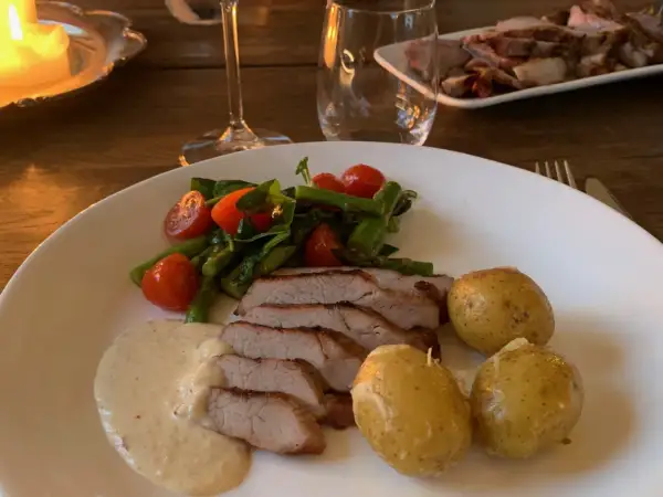 En tallrik med saftigt grillad pluma, serverad med småpotatis, sparris, körsbärstomater och en krämig sås. En härlig måltid!